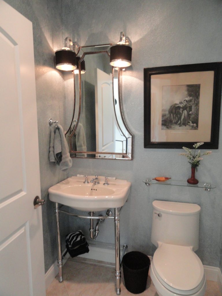 console sink, glass framed mirror, pale blue walls, half bath